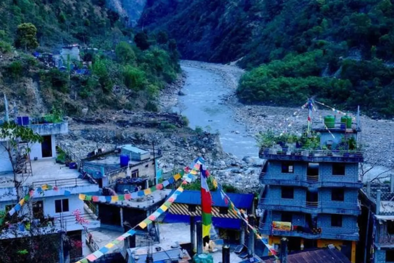 Explore Annapurna Base Camp Classic Trek Vibrant village view with prayer flags and a river valley on the Annapurna Base Camp Classic Trek.