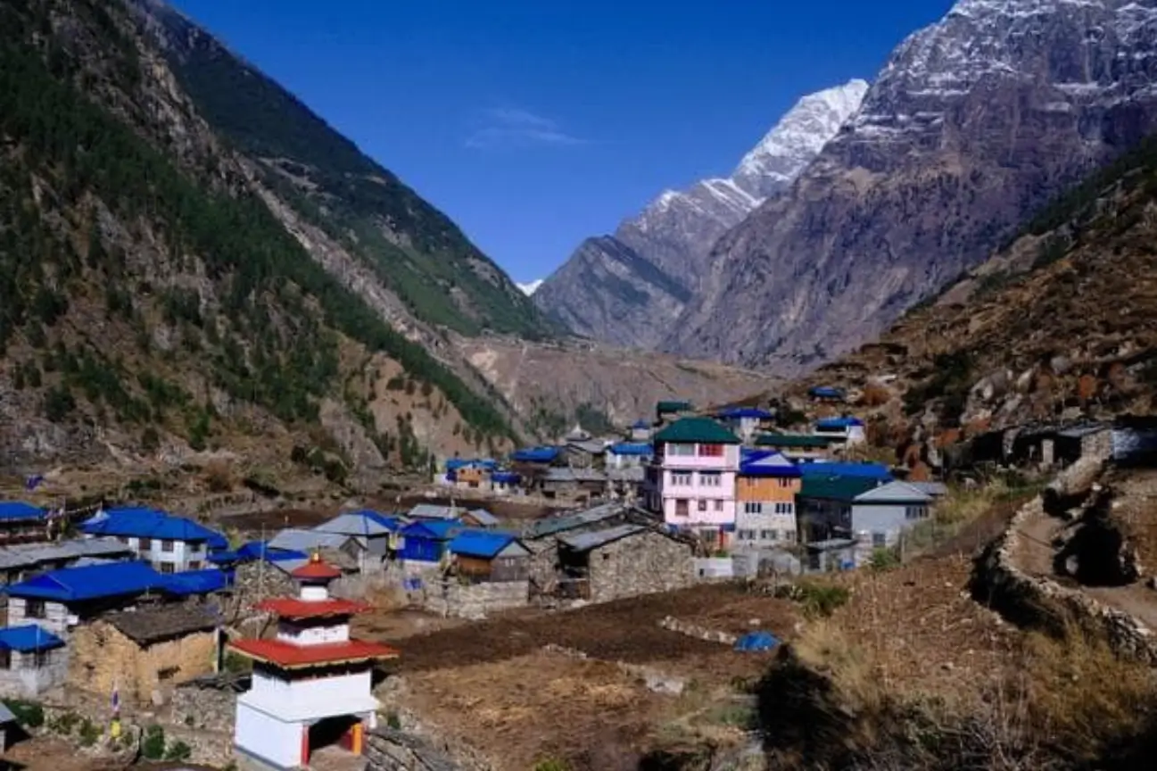 Explore Serene Ghorepani Poon Hill Trek A traditional Himalayan village with colorful roofs nestled in a valley under towering snow-capped peaks on the Serene Ghorepani Poon Hill Trek.