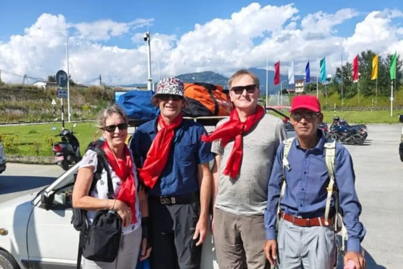 Enjoy Family Friendly Nepal Trekking Annapurna A smiling family group wearing traditional red scarves alongside a local guide on a Nepal Trekking Annapurna trip.